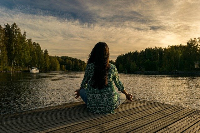 Girl meditating next to water