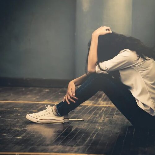 Anxious woman sitting in corner on the floor