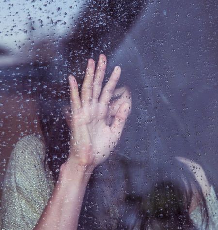 girl crying behind window in rain