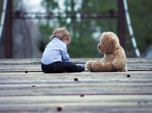 Baby boy sitting on bridge with a teddy bear