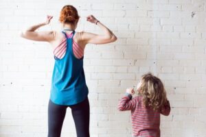 mom standing with daughter showing her muscles